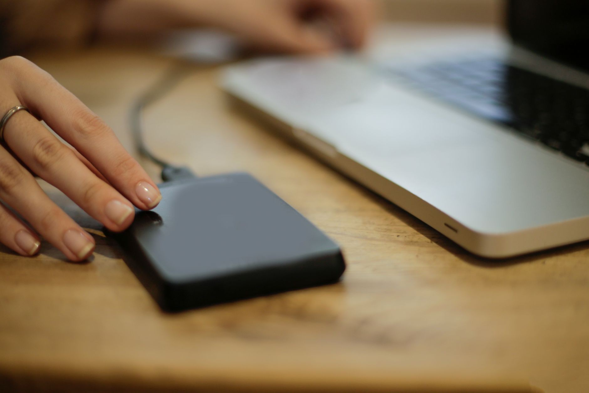 Gros plan sur une personne branchant un disque dur externe à un ordinateur portable sur un bureau.